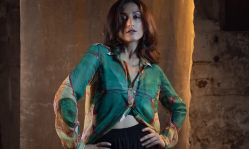 Attractive young woman in elegant casual suit, trousers and and a thin silk shirt. photo in dark colors on a textured wall, warm light